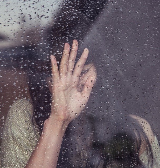 Femme triste derrière une fenêtre