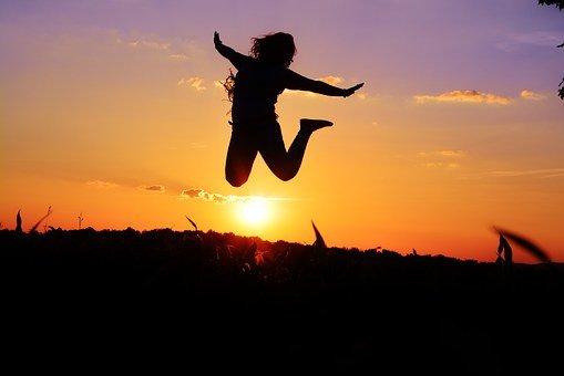 vivre.femme qui saute de joie au coucher du soleil