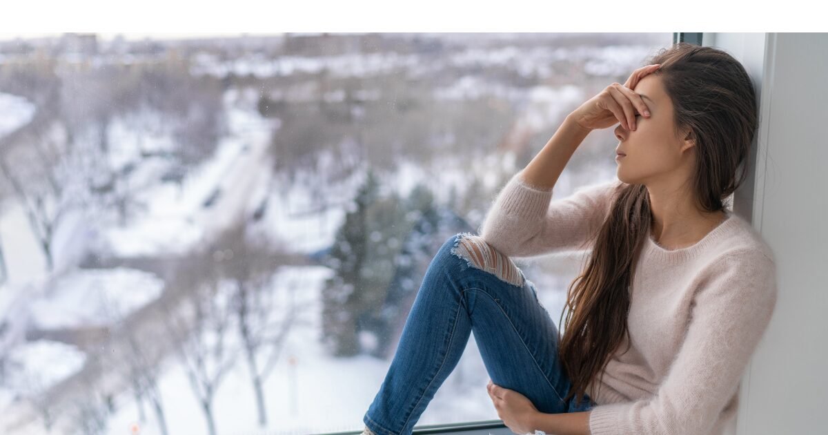femme sur le rebord d'une fenêtre avec une expression de tristesse