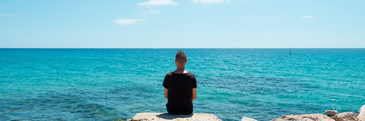 Silhouette d’une personne de dos contemplant la mer, symbole d’introspection et de recherche de sens.