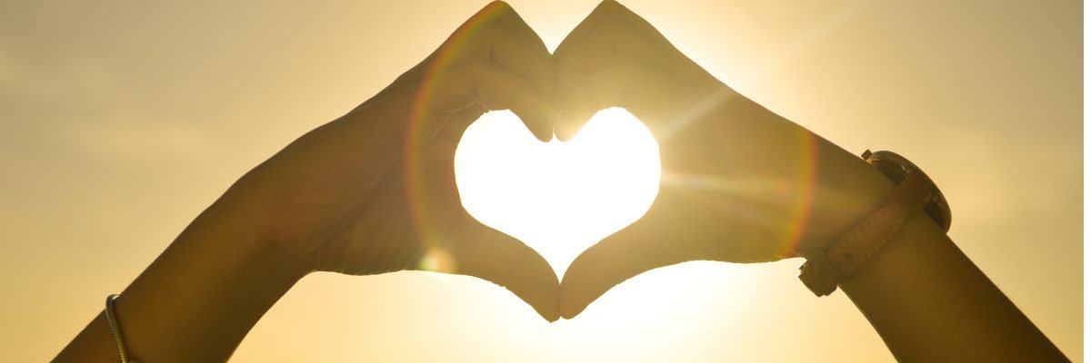 Lever de soleil avec des mains formant un cœur, symbole d’amour de soi et de reconstruction intérieure.