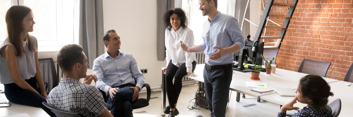 Leader face à son équipe, souriant et engagé, partageant ses idées avec calme et assurance.