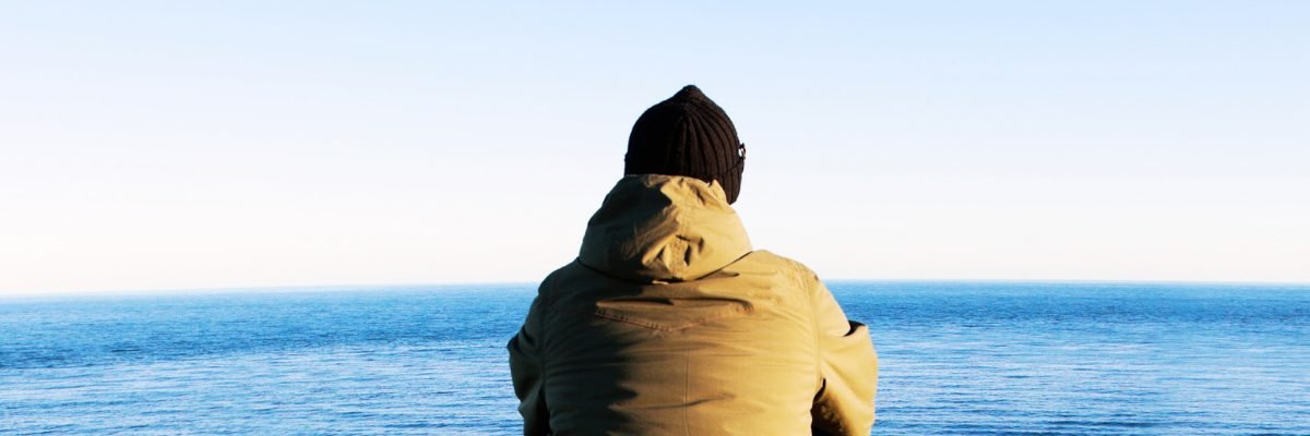 Personne de dos, seule, contemplant l'horizon et la mer symbolisant l'introspection et le silence intérieur