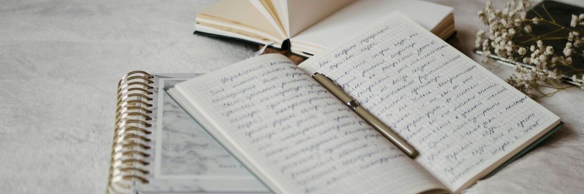 Carnets ouverts et stylo posés, symbolisant l’écriture de ses histoires intérieures et la réflexion sur soi.