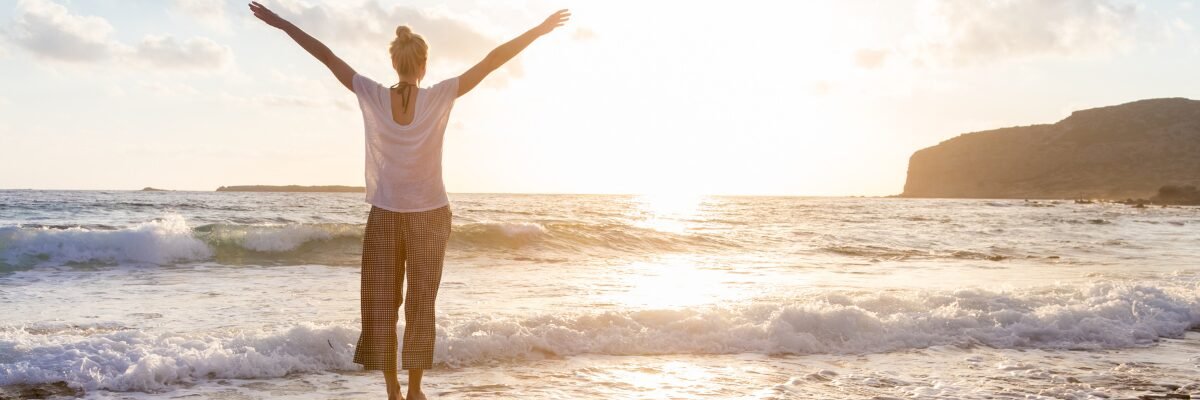 Silhouette de dos, debout sur un rocher face à la mer, bras écartés, symbolisant la liberté, le courage et l’affirmation de soi. 