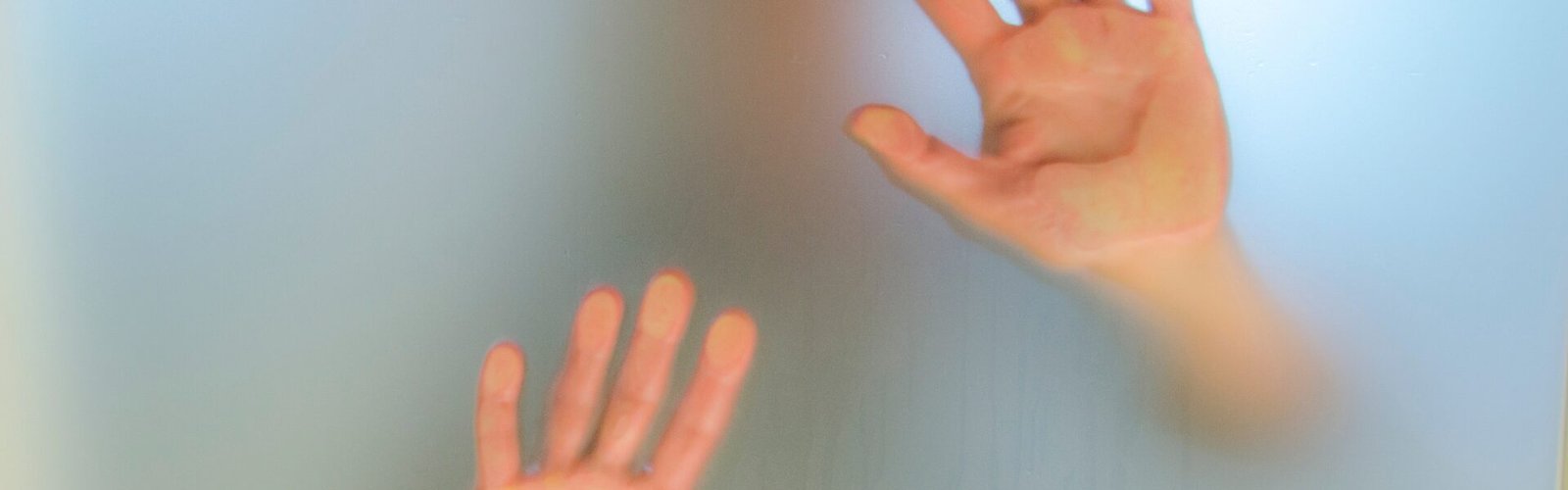 Personne derrière une vitre floue, mains contre le verre, symbolisant quand le subconscient protège en vous bloquant