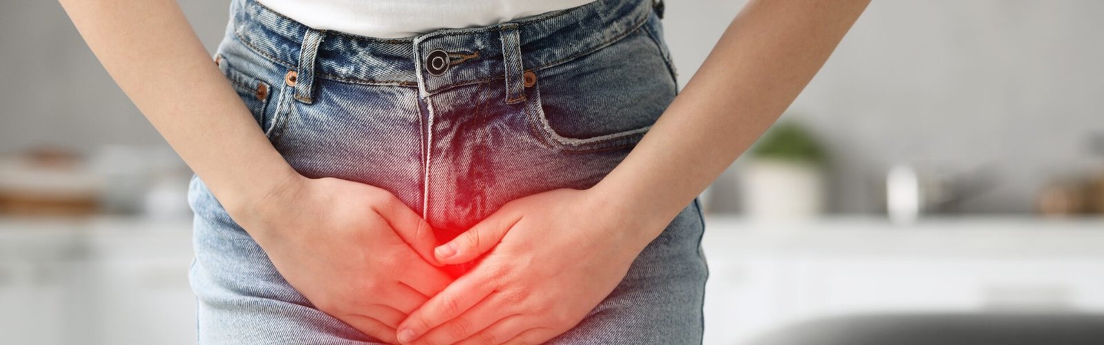 Femme debout se tenant le bas-ventre, illustrant la cystophobie ou peur d’uriner dans un contexte de tension et d’inconfort.