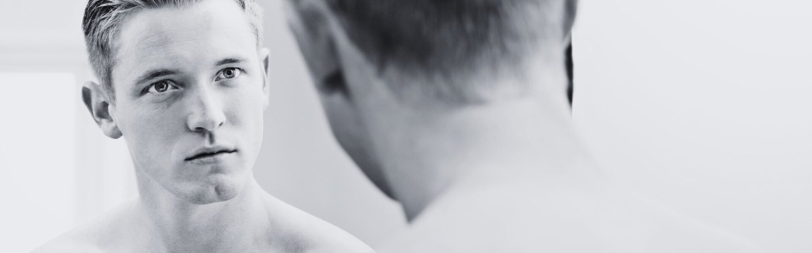 Ce que les autres disent de vous ne vous définit pas : homme face à son reflet dans un miroir, symbole de la recherche d’identité et du regard porté sur soi.