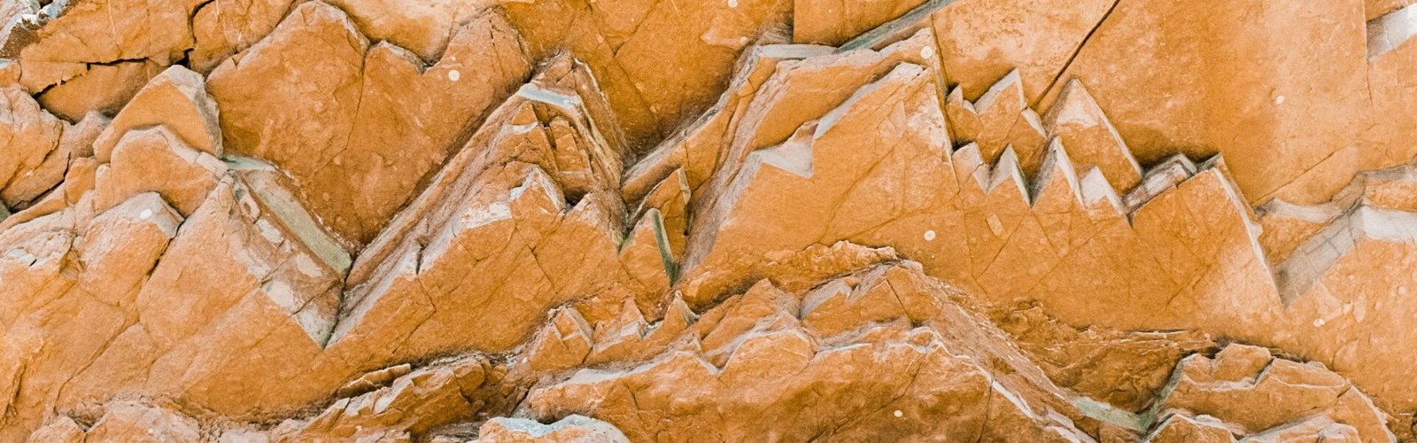 Roche naturelle aux strates visibles dans des tons orange et ocre, symbolisant les différentes couches de l’expérience intérieure et des émotions.
