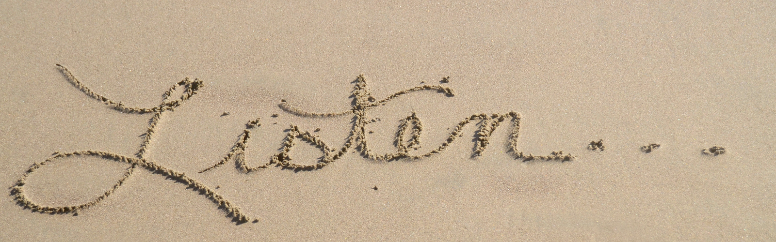 Mot « listen » écrit dans le sable